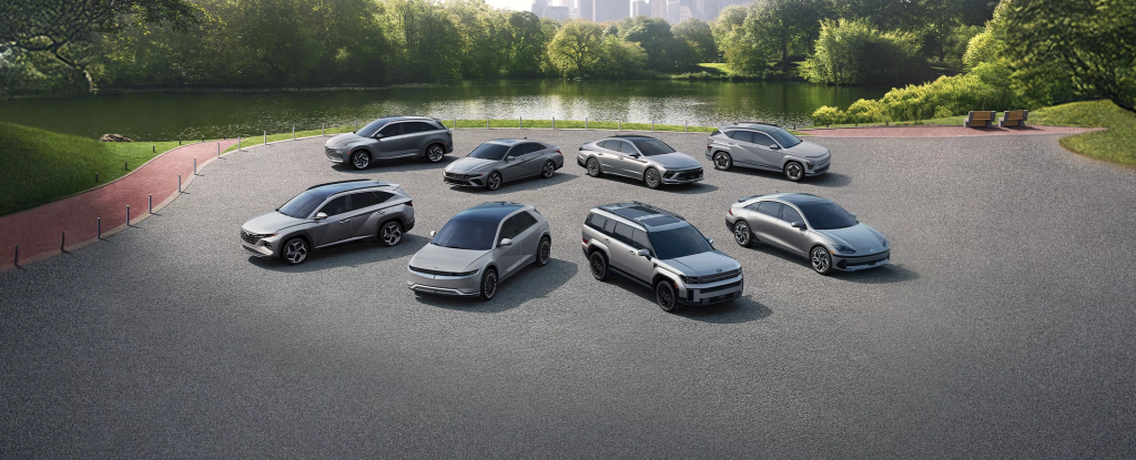 A lineup of Hyundai electric vehicles parked outdoors with lush greenery and trees in the background, highlighting eco-friendly mobility and modern EV design.